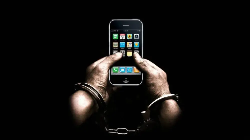 Manos atadas con cadenas y sosteniendo un celular