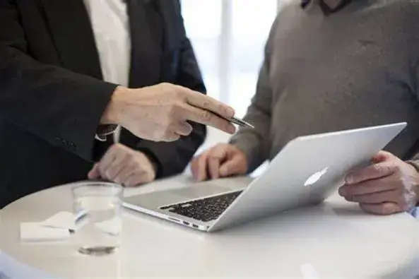 Persona dando asesoramiento a otra con un laptop